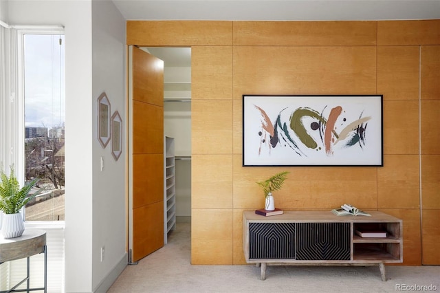 hallway with tile walls and light colored carpet