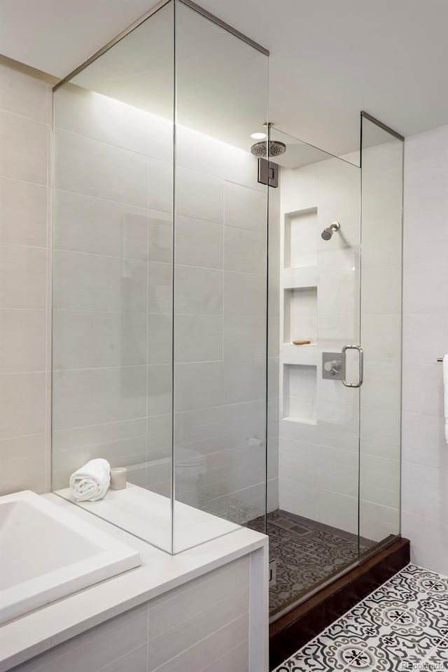 bathroom featuring tile walls, tile patterned floors, and a shower with shower door