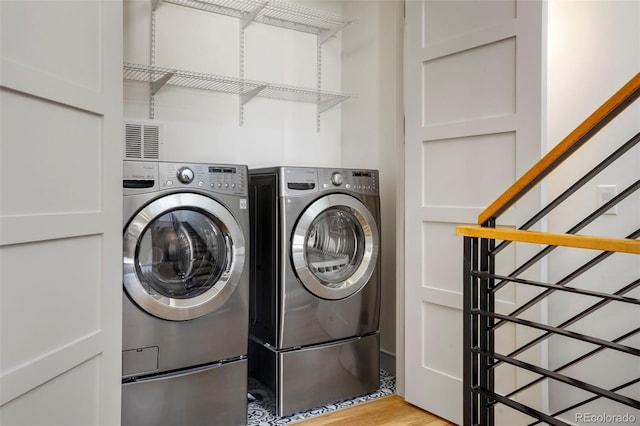 clothes washing area with separate washer and dryer and light hardwood / wood-style floors