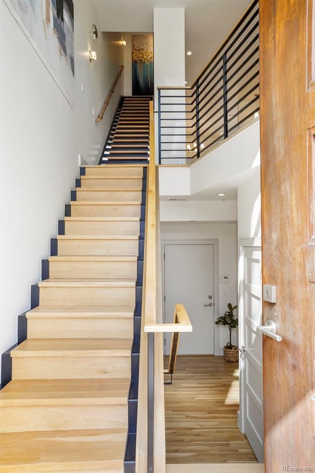 stairs with a high ceiling and hardwood / wood-style flooring