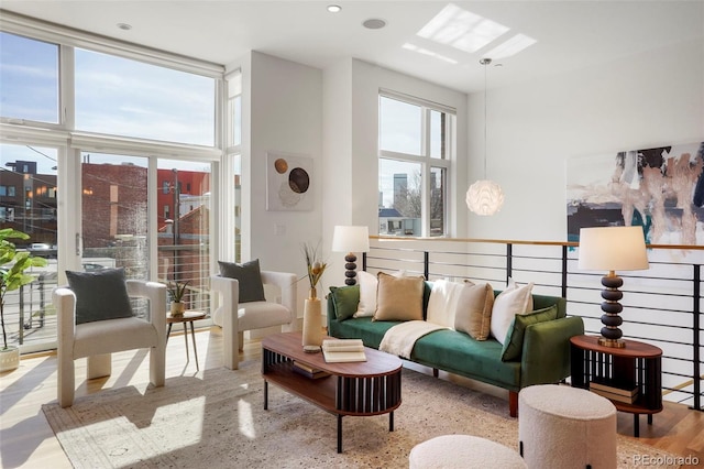 living room with a skylight, floor to ceiling windows, plenty of natural light, and wood finished floors