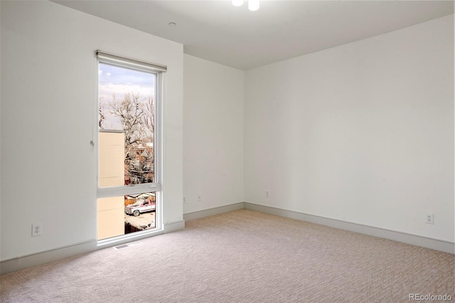 empty room featuring light colored carpet, visible vents, and baseboards