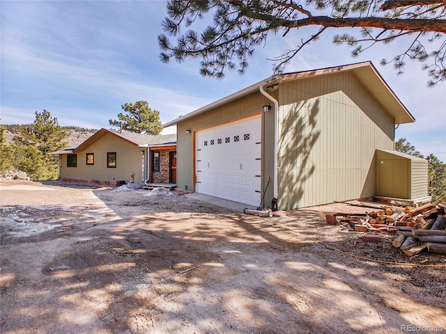 view of home's exterior with an attached garage and dirt driveway