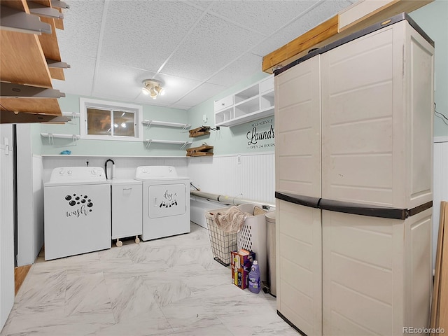 laundry room featuring washer and clothes dryer, laundry area, marble finish floor, and a wainscoted wall