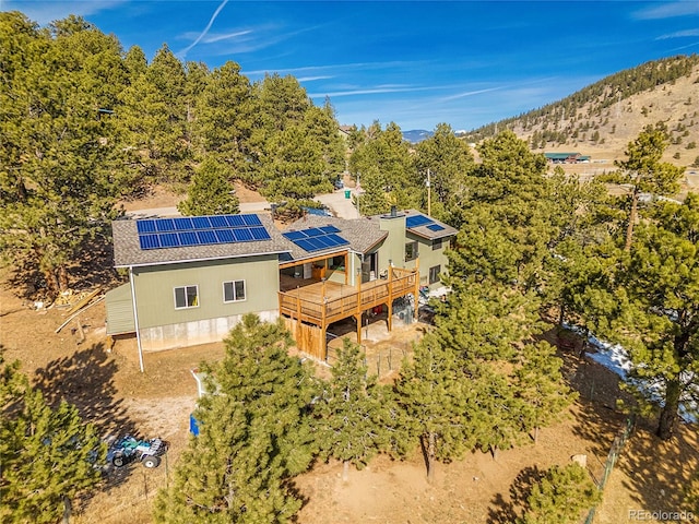 rear view of house with a wooden deck and solar panels