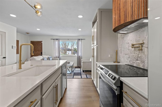 690 S Newark Ct, Aurora, CO 80012 - kitchen with light wood-type flooring, recessed lighting, wall chimney exhaust hood, a sink, and appliances with stainless steel finishes