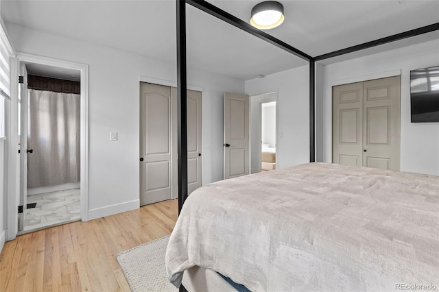 690 S Newark Ct, Aurora, CO 80012 - bedroom featuring baseboards, ensuite bathroom, two closets, and wood finished floors