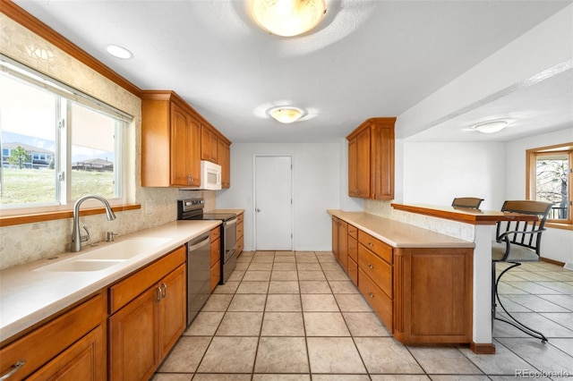 12940 W 75th Ave, Arvada, CO 80005 - kitchen featuring a sink, stainless steel appliances, a breakfast bar area, a peninsula, and tasteful backsplash