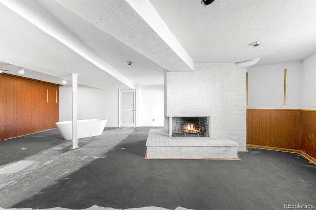12940 W 75th Ave, Arvada, CO 80005 - unfurnished living room with wood walls, a brick fireplace, a textured ceiling, and wainscoting