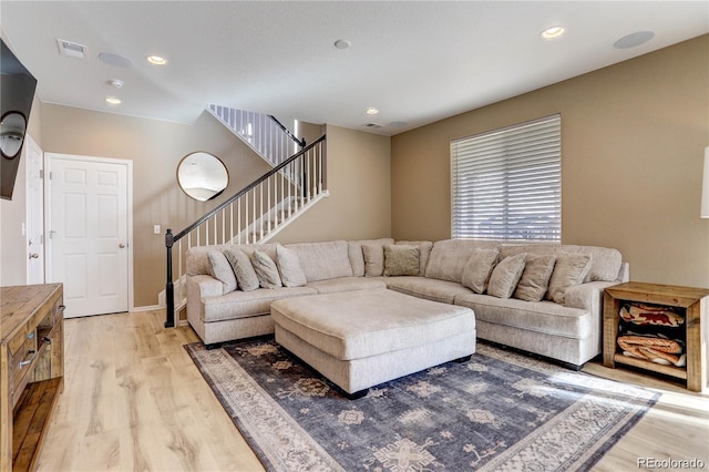 living room featuring light wood-style flooring, stairs, and recessed lighting