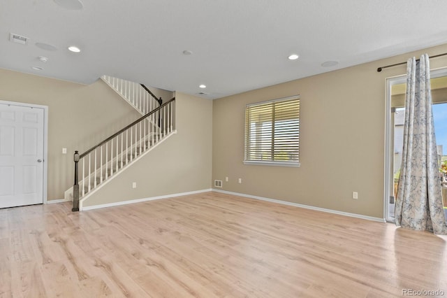 unfurnished living room with light wood-type flooring, stairs, baseboards, and recessed lighting