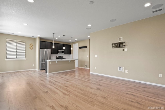 unfurnished living room featuring light wood-type flooring, recessed lighting, and baseboards