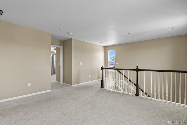 empty room featuring light carpet, baseboards, and recessed lighting