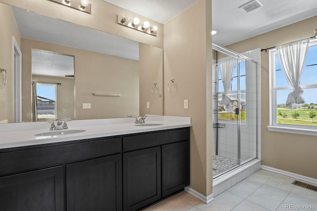 full bath featuring a stall shower, tile patterned flooring, double vanity, and baseboards