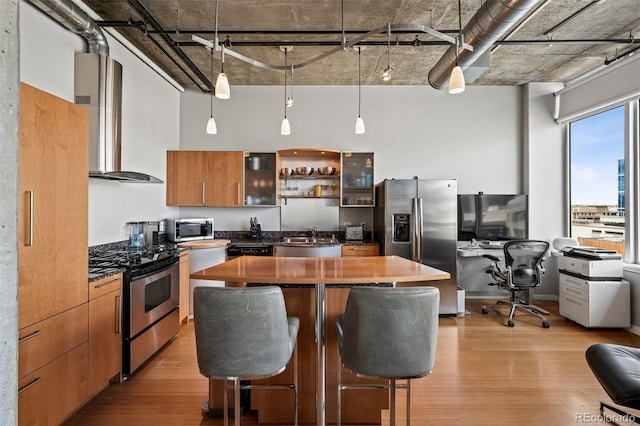 1401 Wewatta St Unit 911, Denver, CO 80202 - kitchen with appliances with stainless steel finishes, wall chimney range hood, a high ceiling, light wood-type flooring, and dark countertops