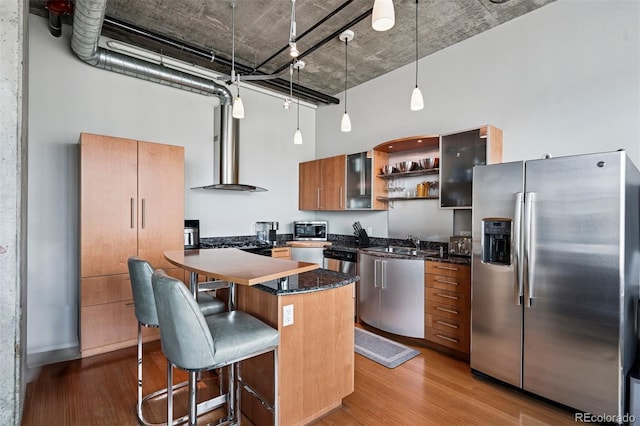 1401 Wewatta St Unit 911, Denver, CO 80202 - kitchen with appliances with stainless steel finishes, wood finished floors, a breakfast bar area, a high ceiling, and pendant lighting
