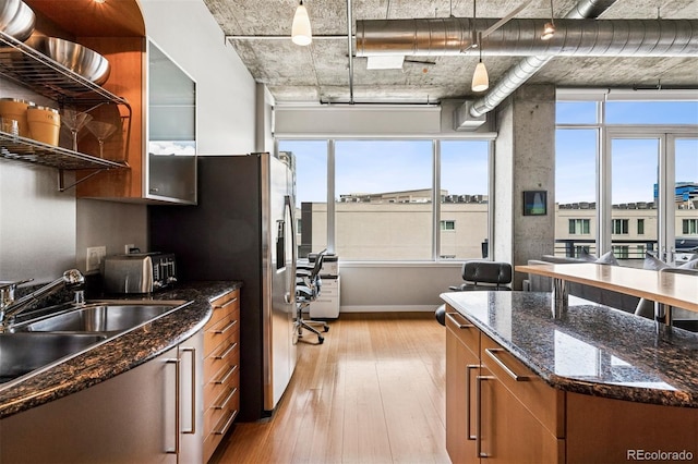 1401 Wewatta St Unit 911, Denver, CO 80202 - kitchen featuring brown cabinets, light wood-type flooring, plenty of natural light, and glass insert cabinets