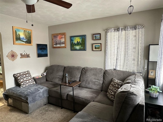 carpeted living room featuring ceiling fan and a textured ceiling