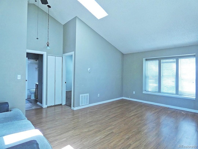 9669 W Chatfield Ave Unit A, Littleton, CO 80128 - living room with wood finished floors, baseboards, a skylight, and high vaulted ceiling