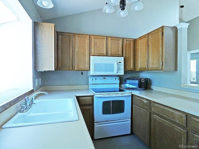 9669 W Chatfield Ave Unit A, Littleton, CO 80128 - kitchen with white appliances, a sink, light countertops, vaulted ceiling, and brown cabinetry