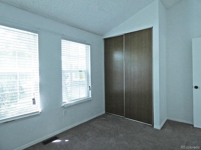9669 W Chatfield Ave Unit A, Littleton, CO 80128 - unfurnished bedroom with a closet, dark colored carpet, a textured ceiling, vaulted ceiling, and baseboards
