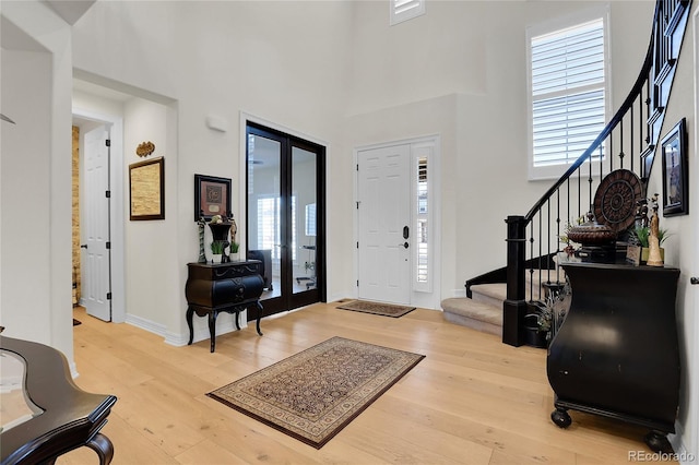 entryway featuring light hardwood / wood-style floors, french doors, and a high ceiling