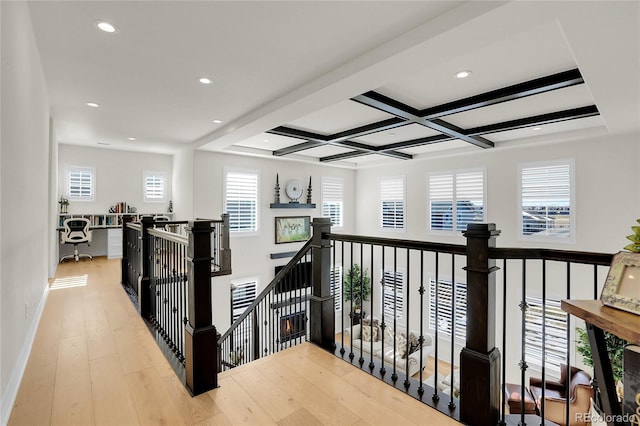 corridor with beam ceiling, coffered ceiling, and light hardwood / wood-style floors