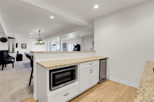 kitchen featuring wine cooler, a kitchen bar, kitchen peninsula, and white cabinets