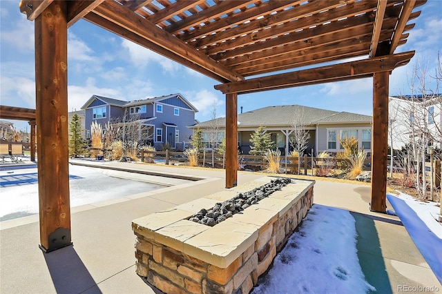 snow covered patio featuring a pergola and a fire pit