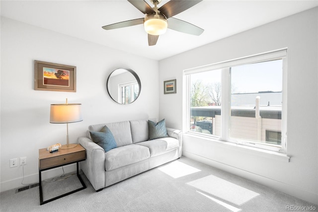 carpeted living area with baseboards, a ceiling fan, and visible vents