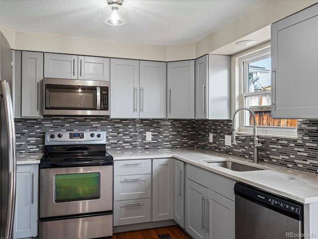 kitchen with a sink, gray cabinets, and stainless steel appliances