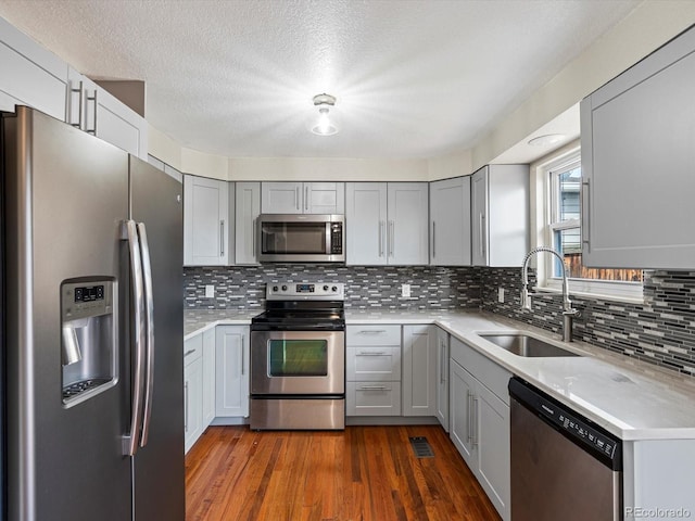 kitchen with light countertops, stainless steel appliances, dark wood finished floors, and a sink