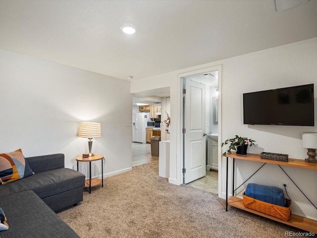 living area with baseboards and light carpet