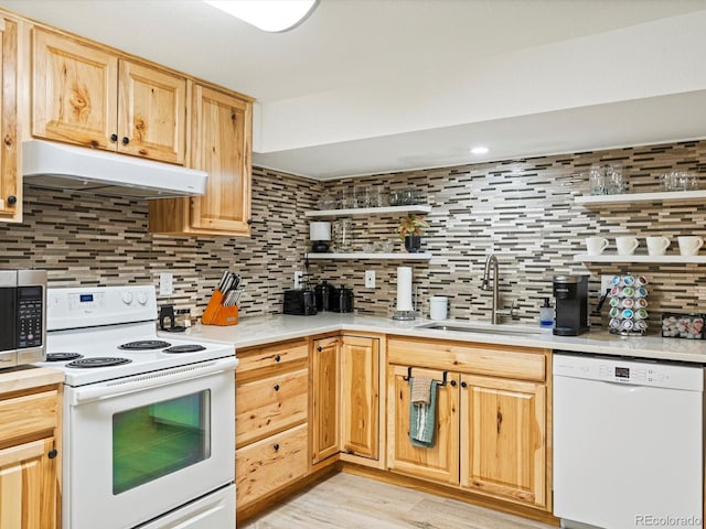 kitchen with a sink, white appliances, light countertops, backsplash, and under cabinet range hood