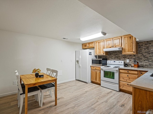 kitchen featuring light wood-style floors, under cabinet range hood, visible vents, and white appliances