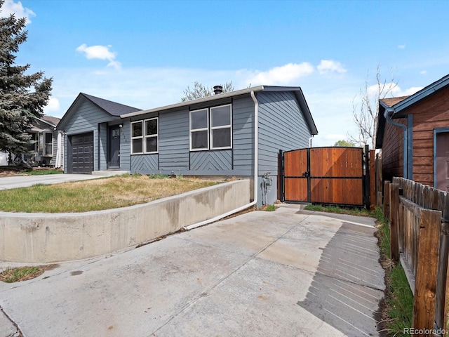 ranch-style home featuring driveway, an attached garage, fence, and a gate