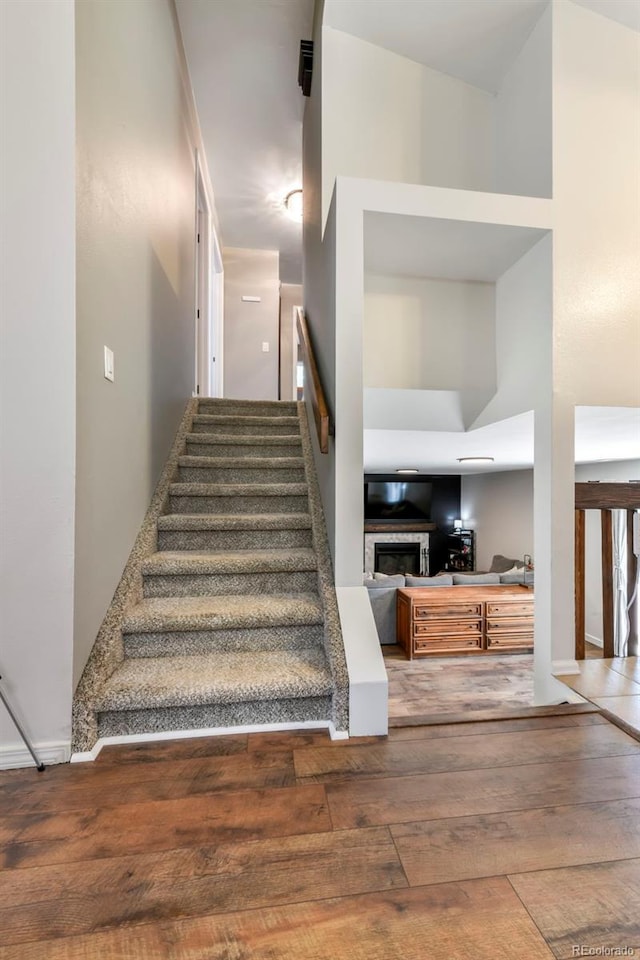 1024 Bromefield Dr, Fountain, CO 80817 - staircase featuring wood-type flooring, a glass covered fireplace, and a towering ceiling