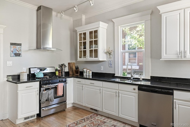 2445 N Franklin St, Denver, CO 80205 - kitchen featuring appliances with stainless steel finishes, wall chimney range hood, crown molding, dark countertops, and white cabinets