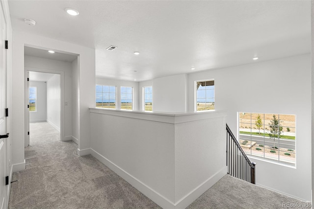 hallway featuring light carpet and a wealth of natural light