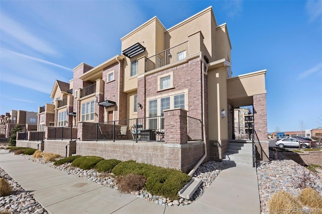 view of property exterior featuring stucco siding, a residential view, and brick siding