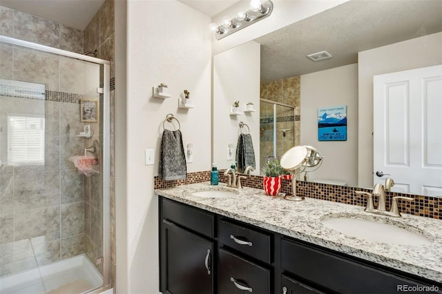 bathroom with a shower stall, double vanity, visible vents, and a sink