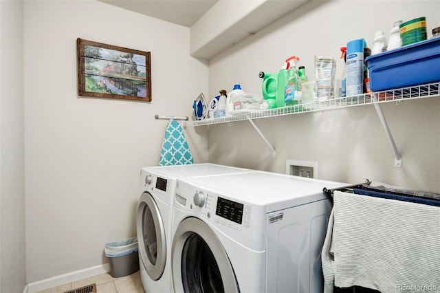 clothes washing area with washer and dryer, laundry area, light tile patterned flooring, and baseboards