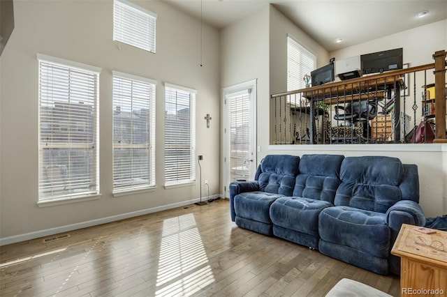 living area featuring visible vents, baseboards, a high ceiling, and hardwood / wood-style flooring