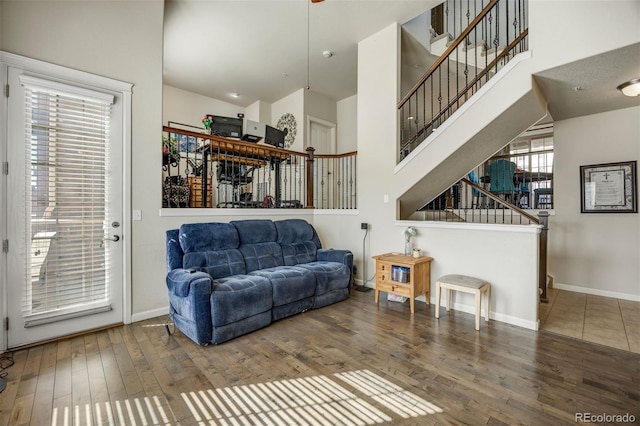 living room featuring baseboards, stairs, a towering ceiling, and wood finished floors