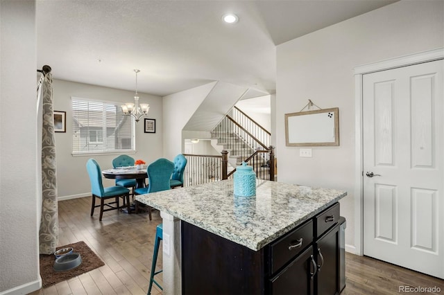 kitchen with a kitchen bar, a notable chandelier, pendant lighting, and wood finished floors