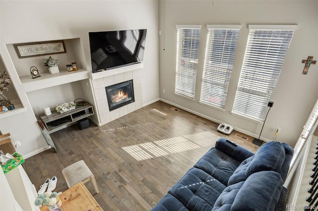 living area featuring visible vents, baseboards, a fireplace, and hardwood / wood-style flooring