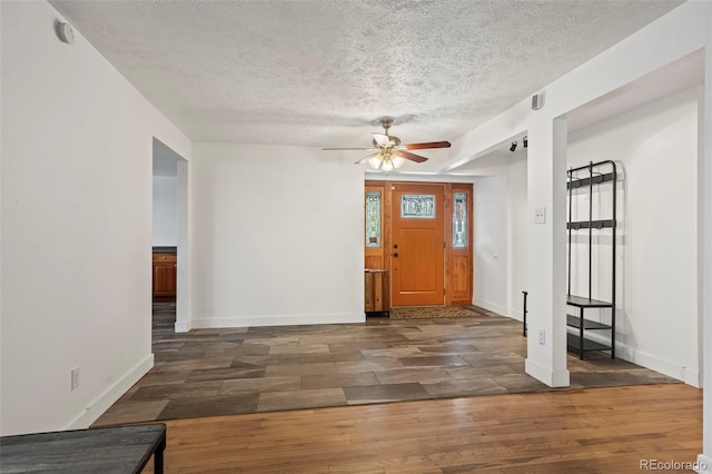 foyer entrance with ceiling fan, dark wood-type flooring, and a textured ceiling