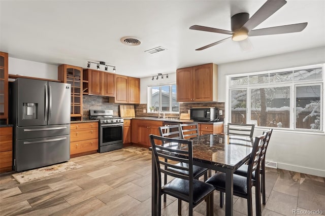 kitchen featuring ceiling fan, sink, stainless steel appliances, backsplash, and light hardwood / wood-style floors