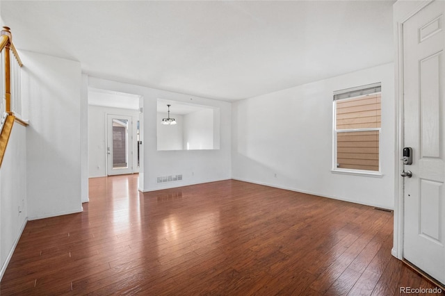 unfurnished living room featuring hardwood / wood-style floors and an inviting chandelier