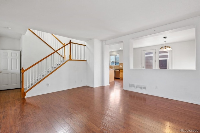 unfurnished living room with wood-type flooring and a chandelier